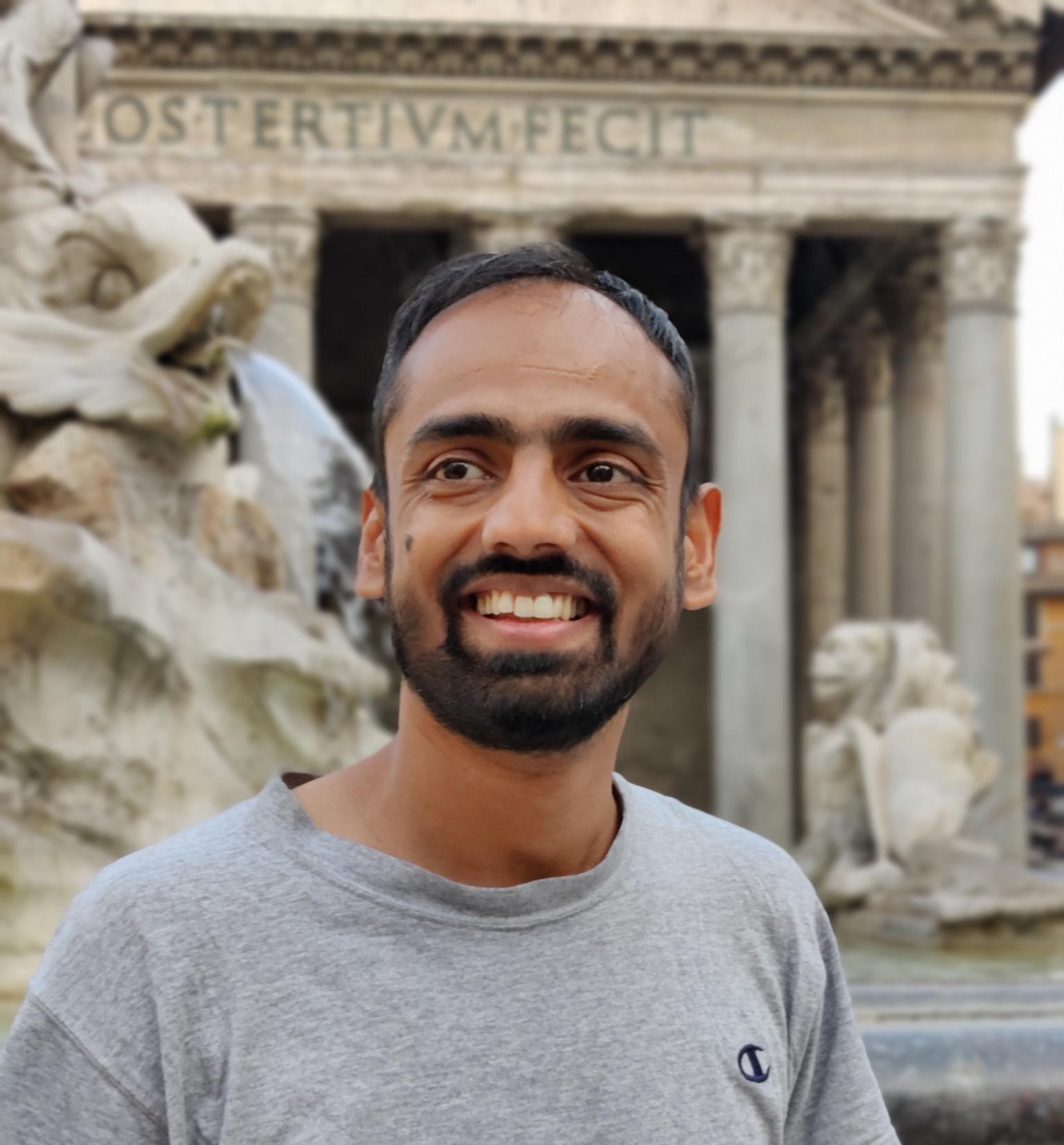 Me wearing a grey t-shirt and smiling in front of the Pantheon in Rome