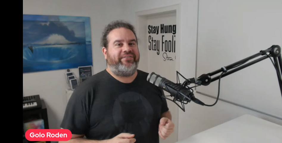 Bearded man speaking into a large microphone